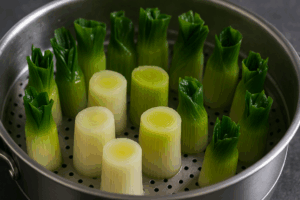 Poireaux vapeur cuits debout dans un panier inox